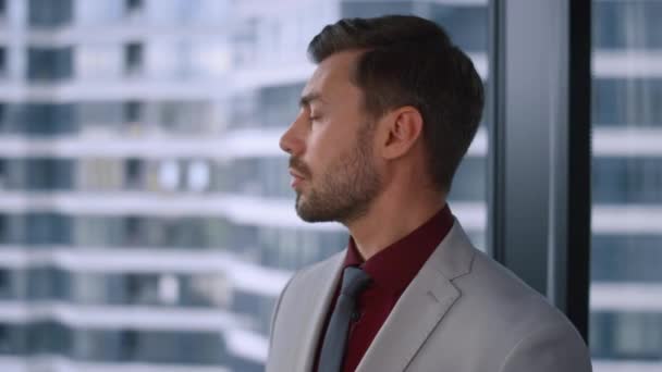 Homem empreendedor olhando câmera posando vestindo terno formal no escritório da janela. — Vídeo de Stock