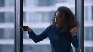 Mutlu kadın yönetici ofis binasının penceresinden iş başarısının tadını çıkarıyor.