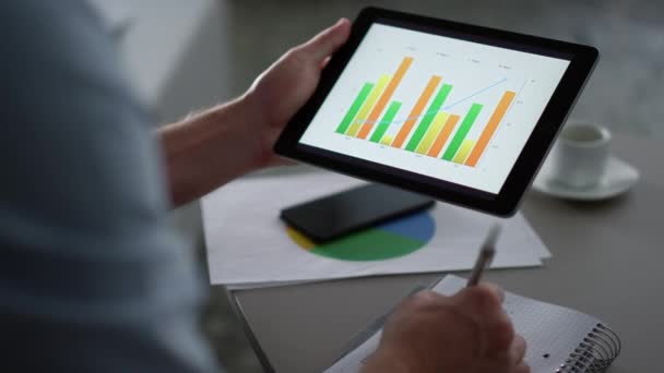 Geschäftsmann recherchiert Diagramm mit Tablet-Computer-Pad im entfernten Büro — Stockvideo