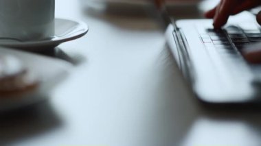 Bilgisayarda klavye yazan eller kafede oturarak online iş projesinde çalışıyor..