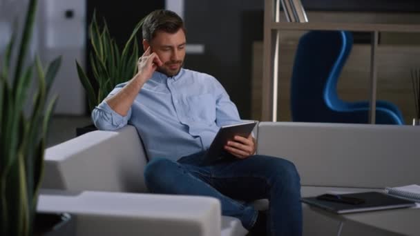Seriózní podnikatel pomocí tabletu rolování informací o novinkách v moderní kanceláři. — Stock video
