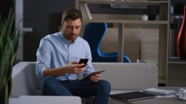 Şirket adamı ev ofisteki telefon görünümlü tablet araştırma verilerini arıyor.