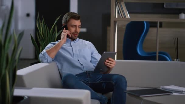 Улыбающийся бизнесмен говорит телефон просматривать планшетные устройства серфинга в Интернете на рабочем месте. — стоковое видео