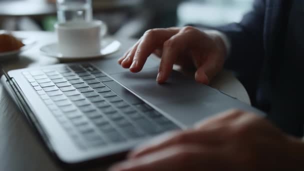 Чоловік працює на комп'ютері онлайн, використовуючи тачпад, переглядаючи бізнес-новини в кафе . — стокове відео