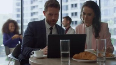 Motivasyonlu iş grubu, kafede dizüstü bilgisayar kullanarak proje başarısını tartışıyor.