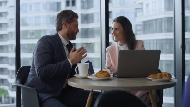 Glad företag par talar diskuterar företagets framgång med hjälp av laptop i caféet. — Stockvideo