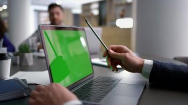 Laptop kullanan iş adamı konferans masasındaki kurumsal verileri analiz ediyor.