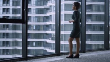 Yönetici kadın ofis binasında cep telefonu kullanarak mesaj yolluyor.