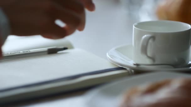 Vrouw hand het nemen van notities schrijven zakelijke ideeën in notitieblok zitten in cafe plaats. — Stockvideo