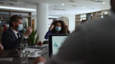 Çok ırklı iş gurubu sohbetleri fikirleri paylaşıyor. İş arkadaşları güvenlik maskesi takıyor..