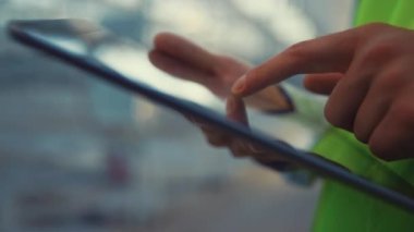 Tableti tutan mühendis ekrana dokunuyor. Ürün bilgilerini kontrol ediyor.