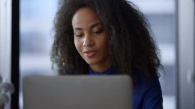 Düşünceli Afro-Amerikan kadın CEO videosu laptopu arıyor ve işyerinde konuşuyor..