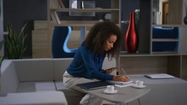Afro-Amerikalı iş kadını iş kadını tableti ofisteki video görüşmeleri üzerine notlar yaz.