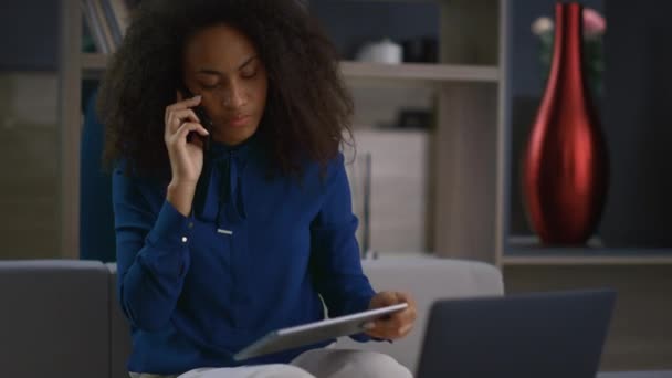 深刻なアフリカ系アメリカ人の最高経営責任者(CEO)の女性が自宅オフィスで電話検索タブレットデバイスを話す — ストック動画