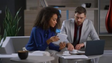 Çok ırklı iş arkadaşları kafe ofisinde dizüstü bilgisayar kullanarak pazarlama projesini tartışıyor.