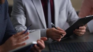 Girişimci elleri ofis masası toplantısına notlar yazarak evrak çalışmalarını yürütür.