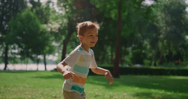 Rapaz feliz a correr no parque verde. Joyful garoto jogando catch-up no fim de semana ao ar livre — Fotografia de Stock