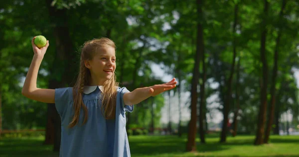 Lächelnde Mädchen werfen Ball auf der grünen Wiese Nahaufnahme. Glückliches Kind spielt Fang im Park. — Stockfoto