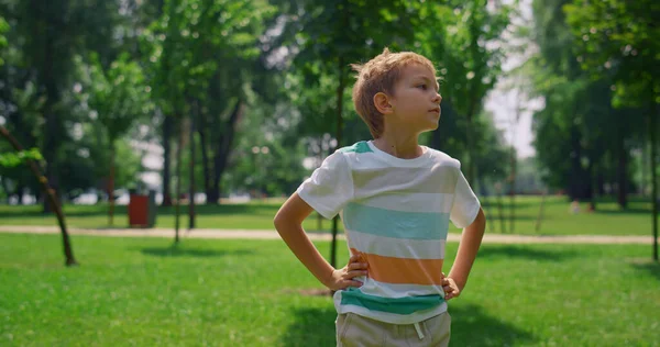 Porträt eines Jungen, der sich auf dem Rasen umsieht. Fröhliches Kind steht auf Wiese. — Stockfoto