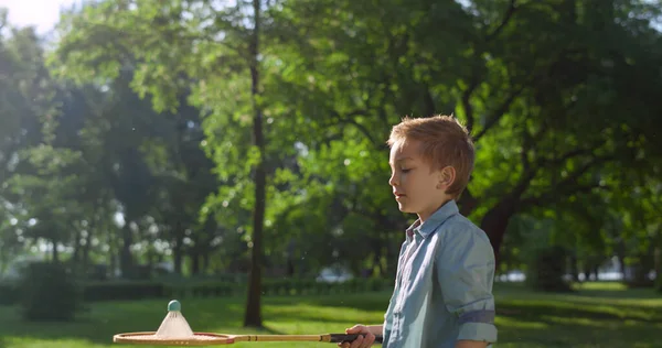 Fokuserad pojke misslyckades med att träffa skyttel på solig dag. Familjepicknick — Stockfoto