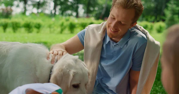 Homem sorridente acaricia labrador na natureza closeup. Família brinca com cachorro em piquenique. — Fotografia de Stock