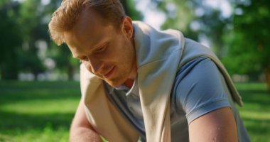 Yakından gülümseyen yakışıklı adam yaz parkında çömelmiş hayvan besliyor..