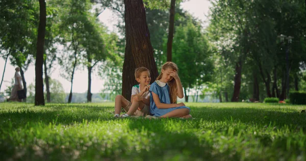 Радостные дети играют под деревом. Улыбающиеся дети веселятся на улице в выходные. — стоковое фото
