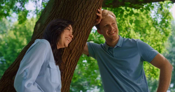 素敵なカップルの木を閉じるにもたれて話す。夫と笑ってる可愛い妻. — ストック写真