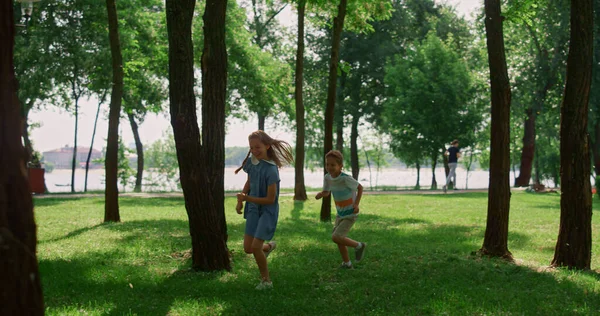 Riendo niños corriendo en el soleado prado. Los niños felices juegan a ponerse al día en el parque. —  Fotos de Stock