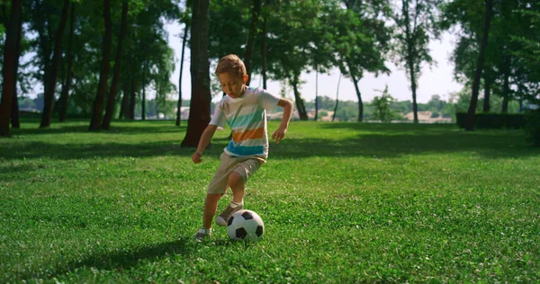 Energiczny chłopak rozgrzewający się przed meczem piłki nożnej. Skupiona zabawa dla dzieci na boisku. — Zdjęcie stockowe