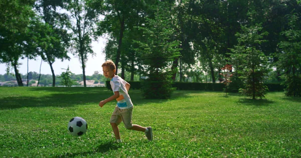 축구 공을 치는 데만 집중하는 꼬마. 여름 공원에서 신선 한 공기를 훈련시키는 소년. — 스톡 사진