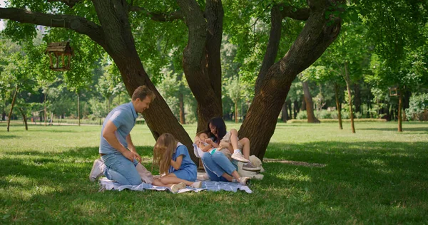 Cheerful parents tickling kids on picnic. Family amusement on summer weekend. — Stock Photo, Image