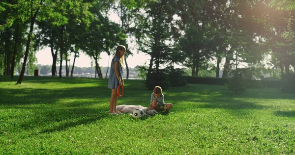 Fröhliche Geschwister streicheln Golden Retriever im Park. Hund liegt auf der grünen Wiese. — Stockfoto