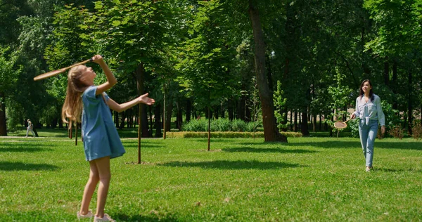 Fröhliches Mädchen spielt Badminton mit Mutter im Park. Aktives Familienerholungskonzept. — Stockfoto