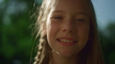 Altın güneş ışığında poz veren neşeli sarışın kız. Kameraya bakan neşeli çocuk. 