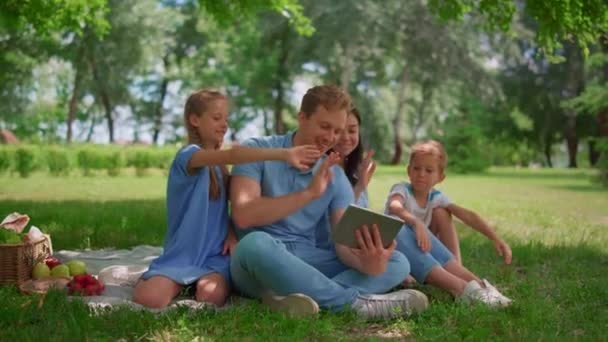 Le mani d'onda di famiglia sorridenti comunicano usando targa su natura in giorno estivo. — Video Stock