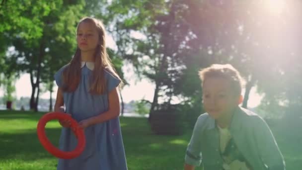 Zwei fokussierte Geschwister, die im goldenen Sonnenlicht des Parks in Nahaufnahme laufen. Kinder gehen weg. — Stockvideo