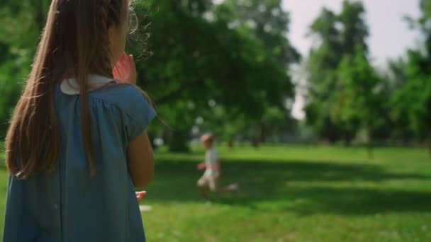 Chica graciosa arañando la nariz en Sunny Park. Lindo niño limpiando la cara vista trasera. — Vídeos de Stock