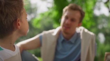 Gülümseyen baba oğluyla doğada konuşuyor. Yakın çekim. Mutlu aile dinlenme konsepti.