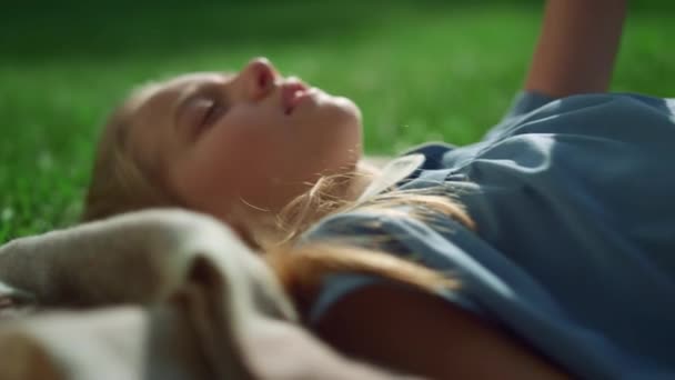 Усміхнена блондинка лежить на ковдрі на зеленому полі тримає руку крупним планом . — стокове відео