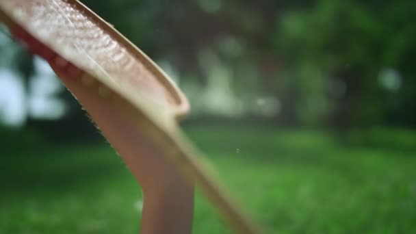 Крупним планом рука тримає дерев'яну бадмінтонну ракетку в золотому сонячному світлі в парку . — стокове відео