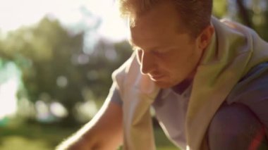 Yakından, çömelmiş yere bakan çekici bir adam. Eller pedala.