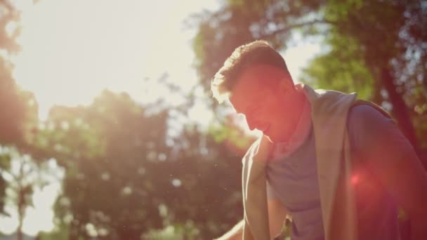Улыбающийся мужчина дарит розовый пуллер игрушке дразнит золотистого ретривера в парке солнечного света — стоковое видео