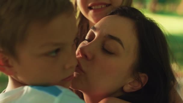 Любящая мать целует мальчика на пикнике крупным планом. Счастливая женщина, проявляющая любовь к детям. — стоковое видео