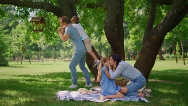 Father hold on back little son on picnic. Parents play with kids on summertime. — Stock Video