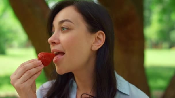 Mladá žena jí strowberry na pikniku zblízka. Bruneta kousnout čerstvé červené bobule. — Stock video