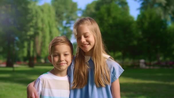 Smiling girl hug little brother looking in camera. Boy unwilling to embrace. — Stock Video