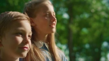 İki gülümseyen çocuk uzaktan bakıyor. Sarışın kardeşler sarılıyorlar..