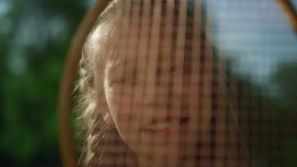 Χαμογελαστή κοπέλα που ψάχνει κάμερα μέσα από δίχτυ ασφαλείας. Όμορφο παιδί ποζάρει ήλιο — Αρχείο Βίντεο