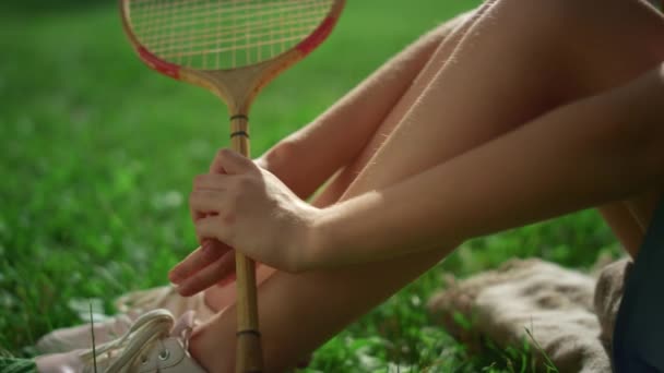 Closeup menina pernas mão segurando badminton raquete no parque. Kid sentar cobertor sozinho — Vídeo de Stock